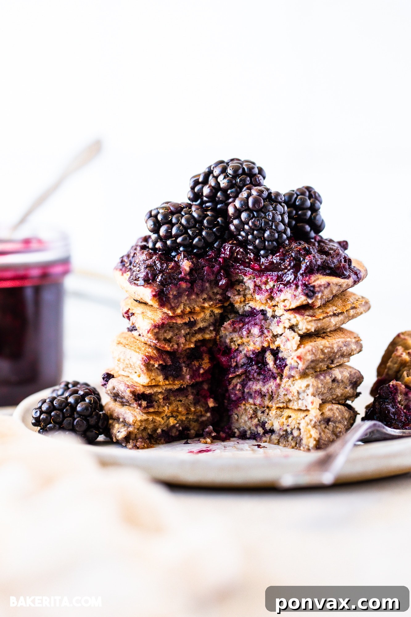 Berrylicious Vegan GF Pancakes 2 A stack of fluffy gluten-free vegan blackberry pancakes topped with fresh blackberries and maple syrup.