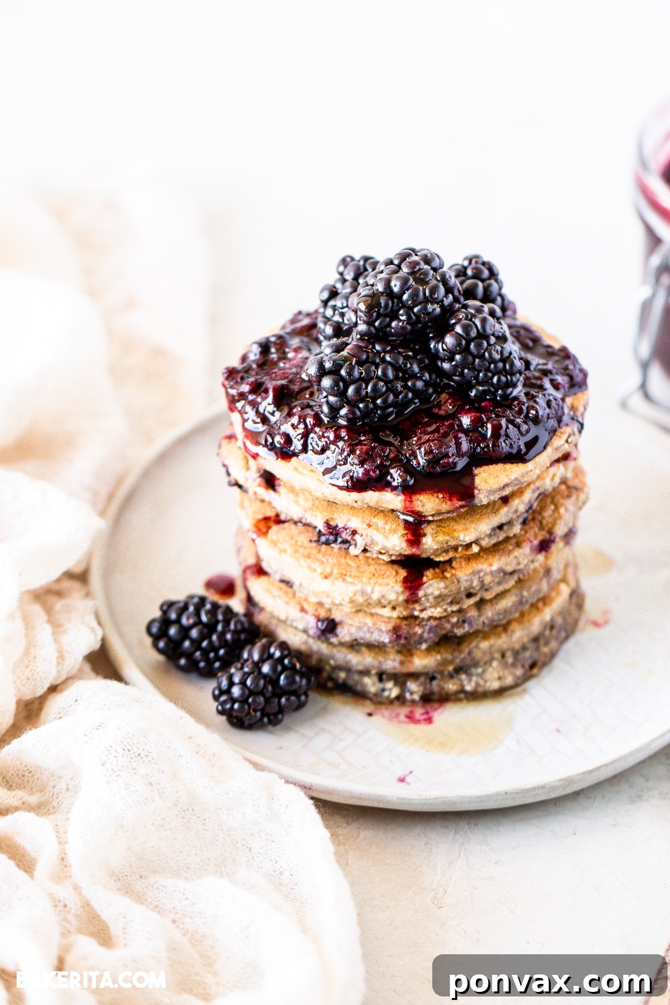 Berrylicious Vegan GF Pancakes 3 Close-up of fluffy blackberry pancakes with a sprinkle of powdered sugar.