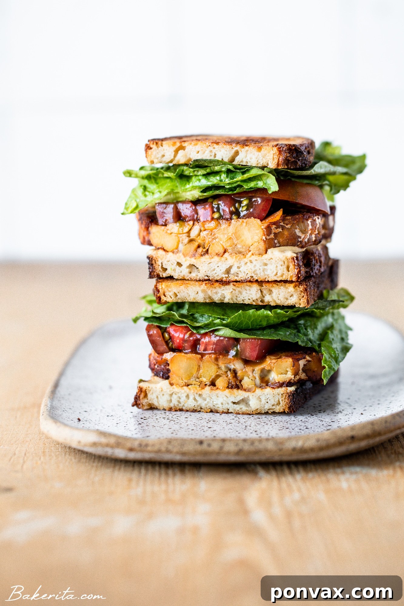 A delicious and vibrant Vegan Tempeh BLT sandwich on a rustic wooden board, ready to be enjoyed.