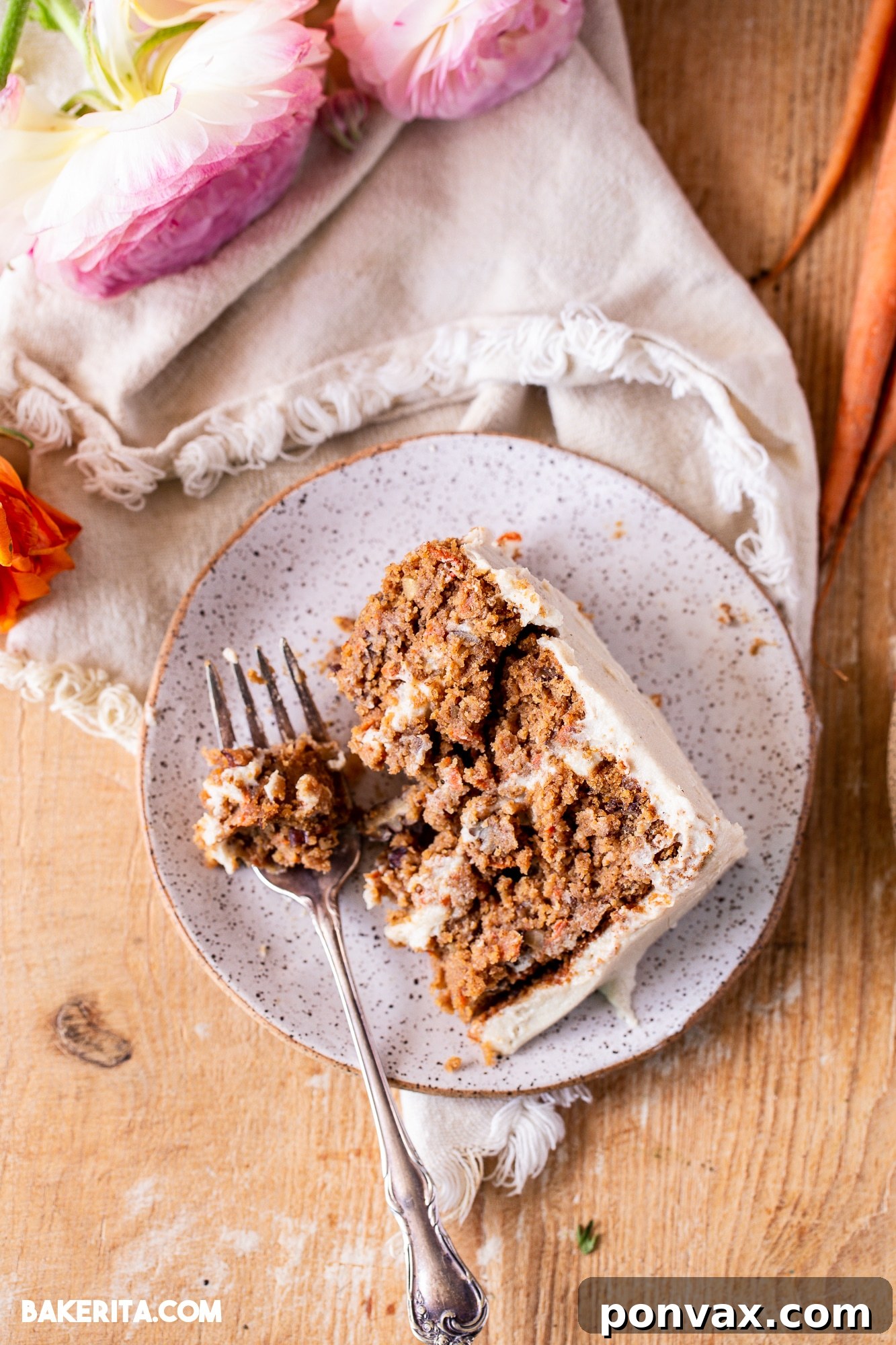 Close-up of a slice of gluten-free vegan carrot cake, showcasing its moist texture and generous frosting.