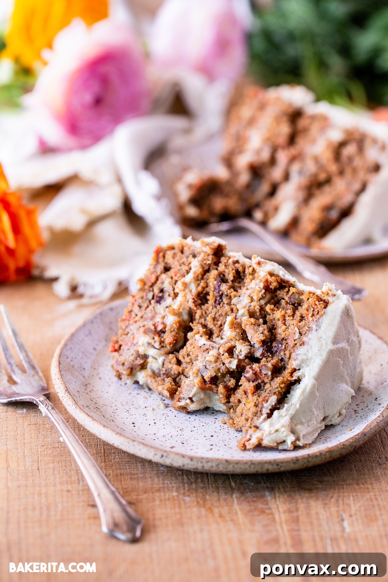 A slice of gluten-free vegan carrot cake being served, with a fork digging into the moist layers.