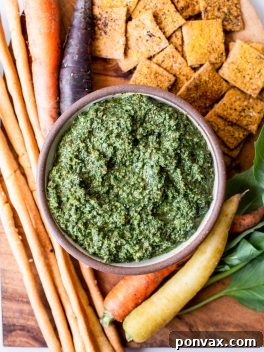 Close-up of a glass jar filled with green carrot top pesto, vibrant and ready to use.