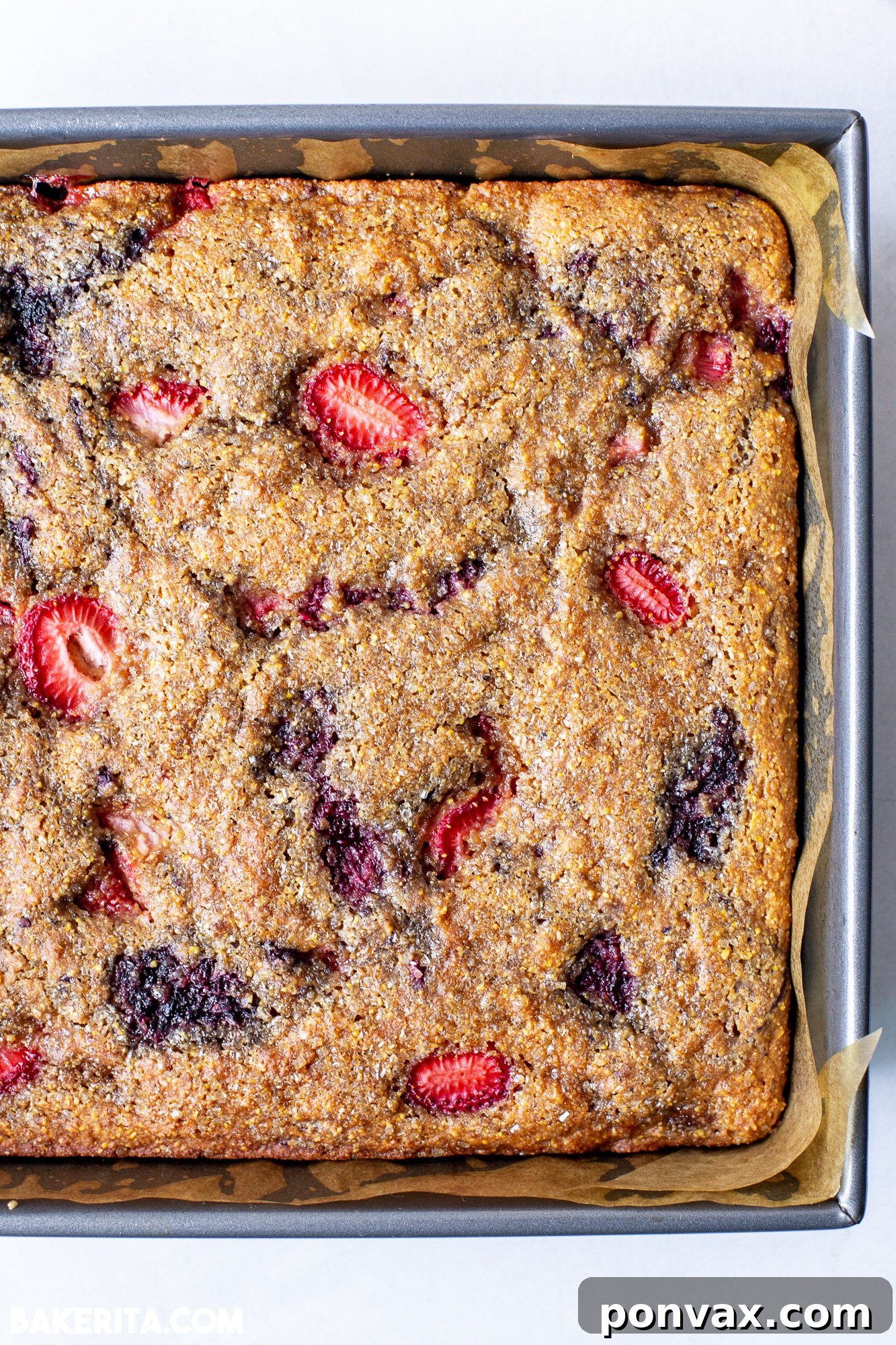 A close-up of a single slice of Berry Cornmeal Cake, showing its fluffy interior.