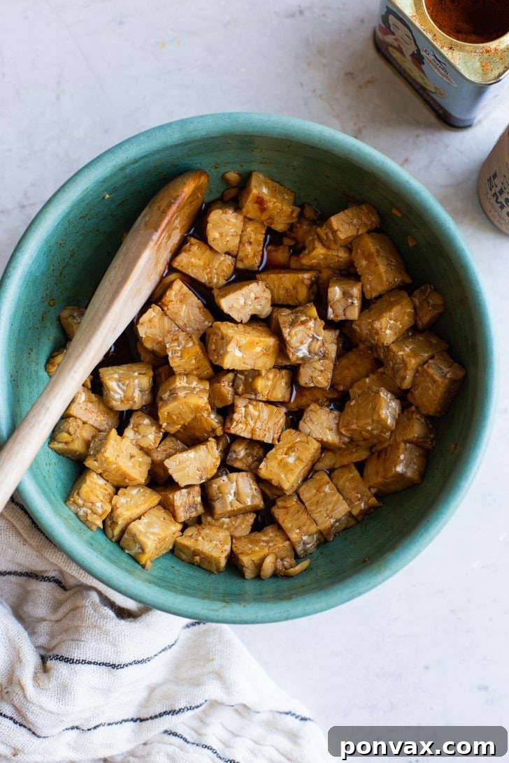 Close-up of uncooked tempeh strips marinating in a bowl