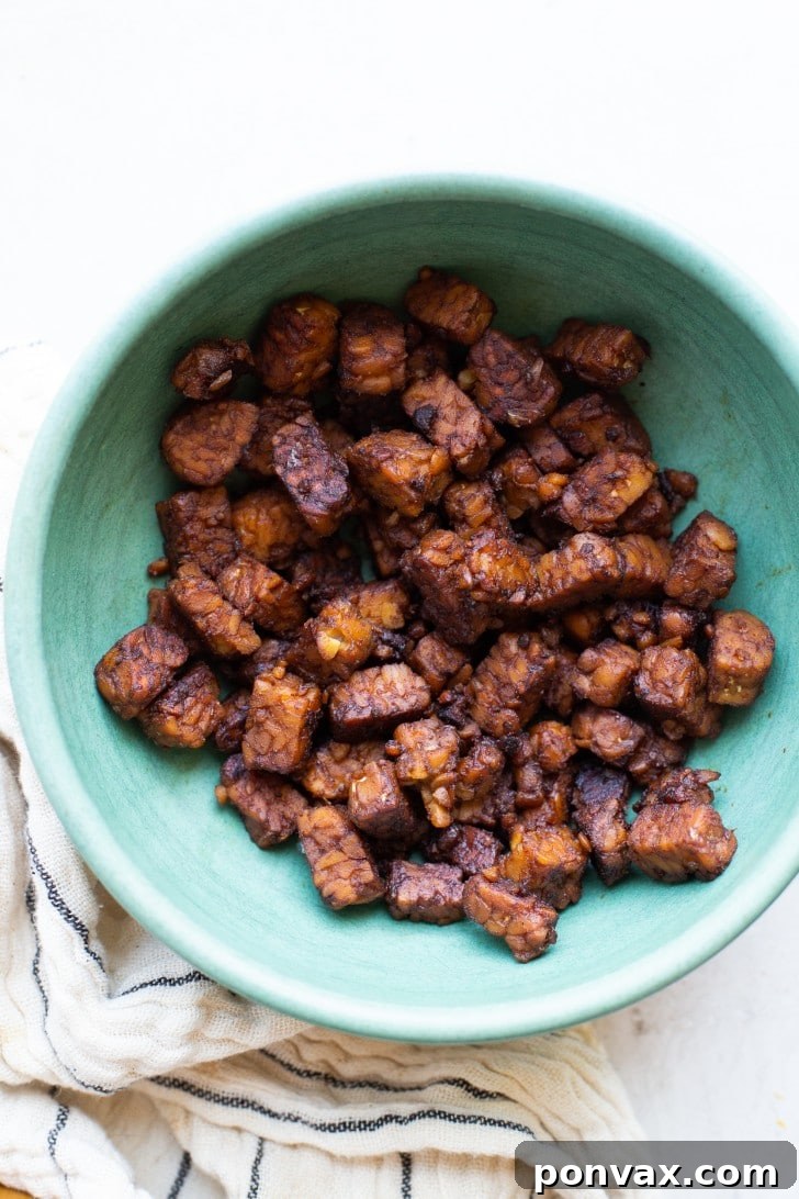 Tempeh bacon strips in a pan, coated in a sticky sauce