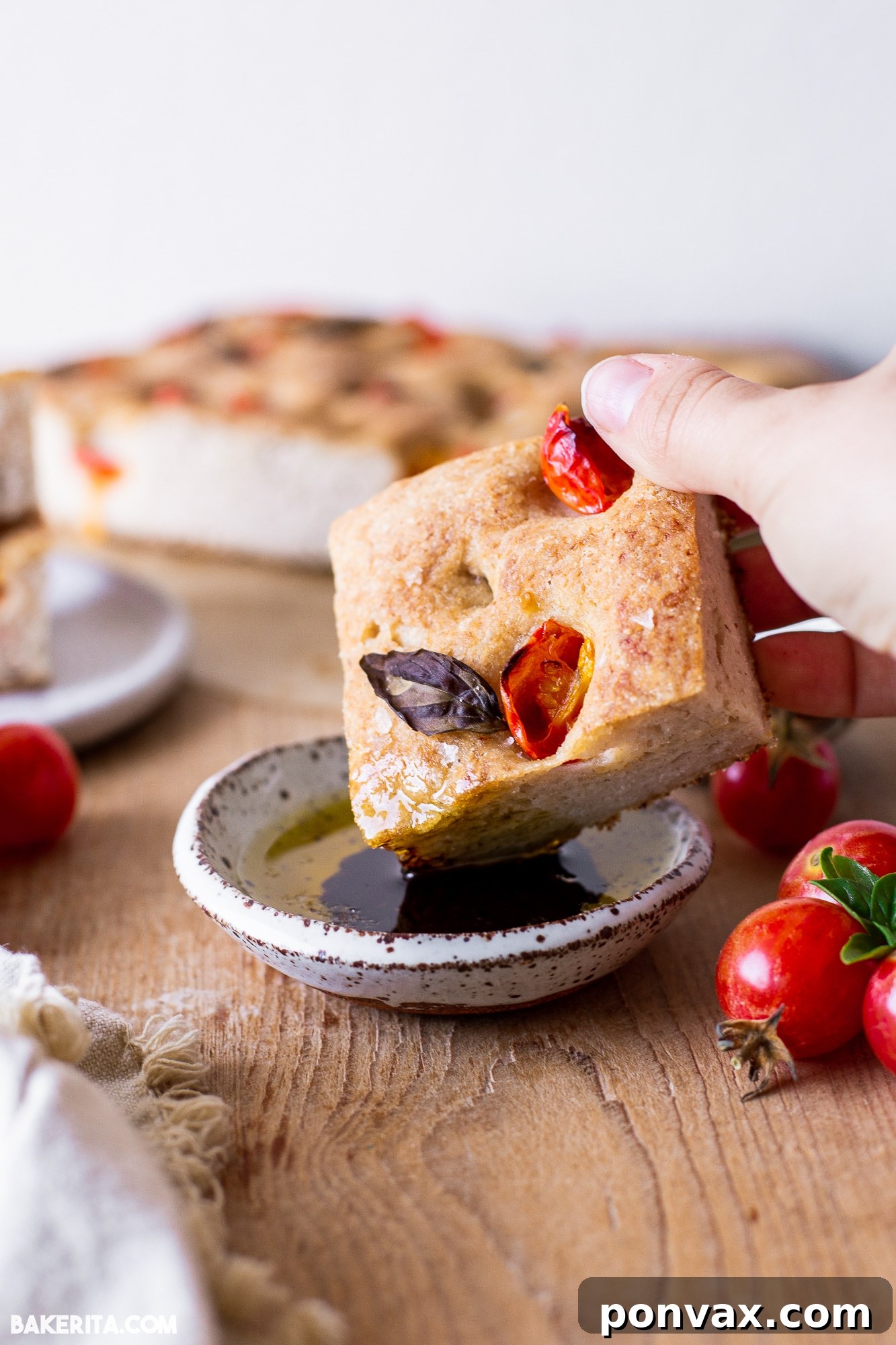 Hand pulling apart a piece of gluten-free sourdough focaccia, showing its soft interior and crispy exterior.