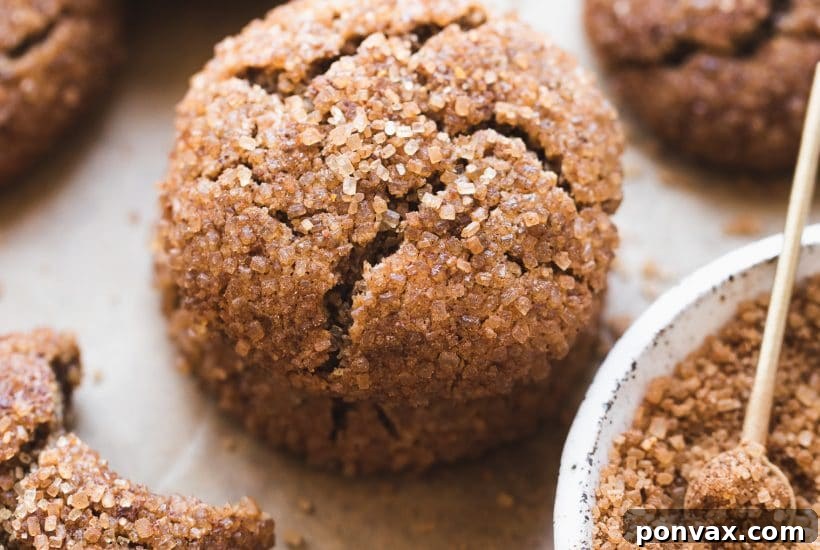 25+ Delicious Vegan Cookie Recipes 10 A stack of golden brown chai sugar cookies, sprinkled with cinnamon, on a wooden board with a cozy tea setup in the background.