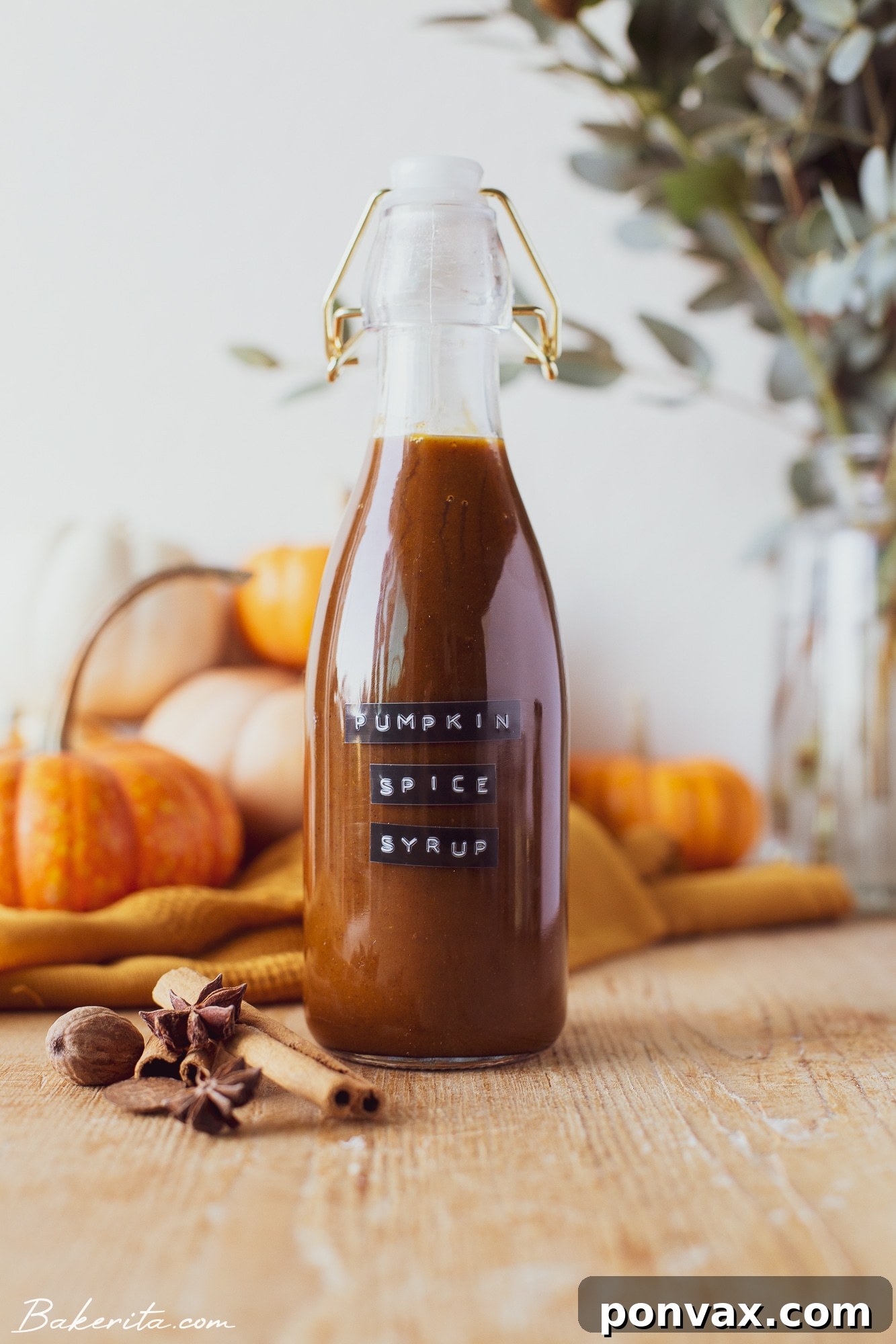 A bottle of homemade healthy pumpkin spice syrup next to a spoon with syrup.