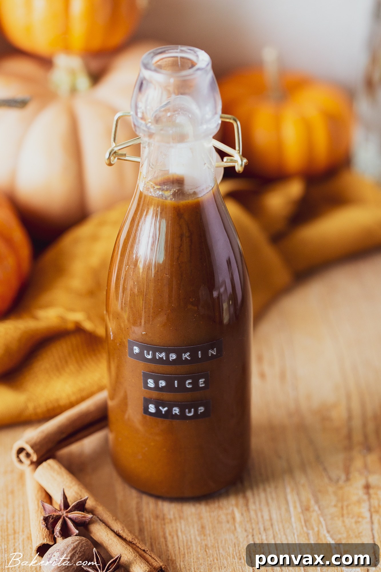 A glass of pumpkin spice latte garnished with a cinnamon stick and star anise.
