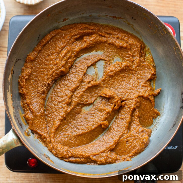 Pumpkin puree and pumpkin pie spice cooking in a saucepan.