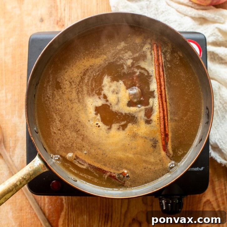 Whip Up Your Own Apple Syrup 5 Apple syrup simmering in a saucepan, reducing in volume.
