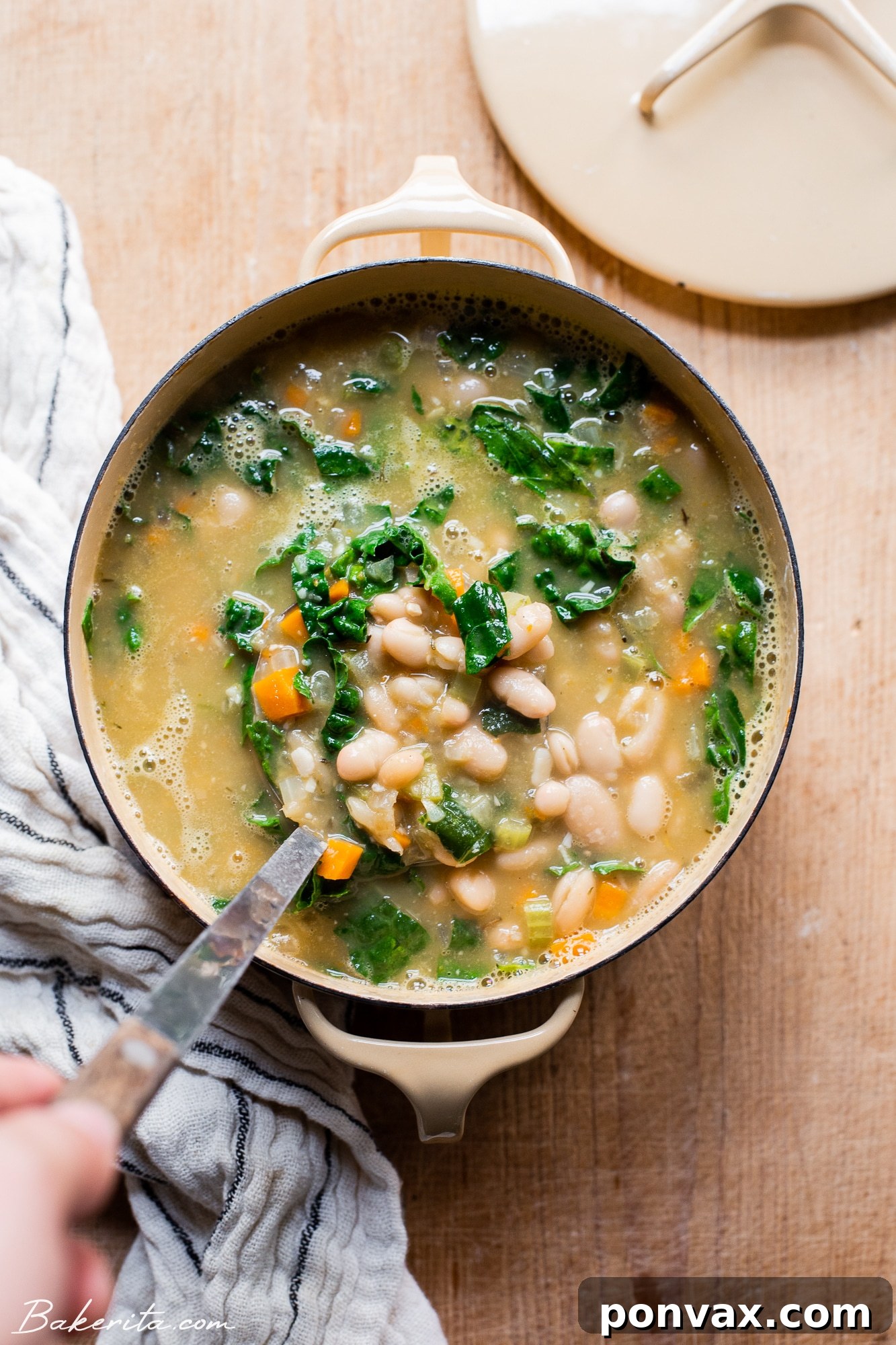 Hearty Vegan Kale and White Bean Soup 2 A bowl of creamy vegan kale and white bean soup garnished with fresh herbs.
