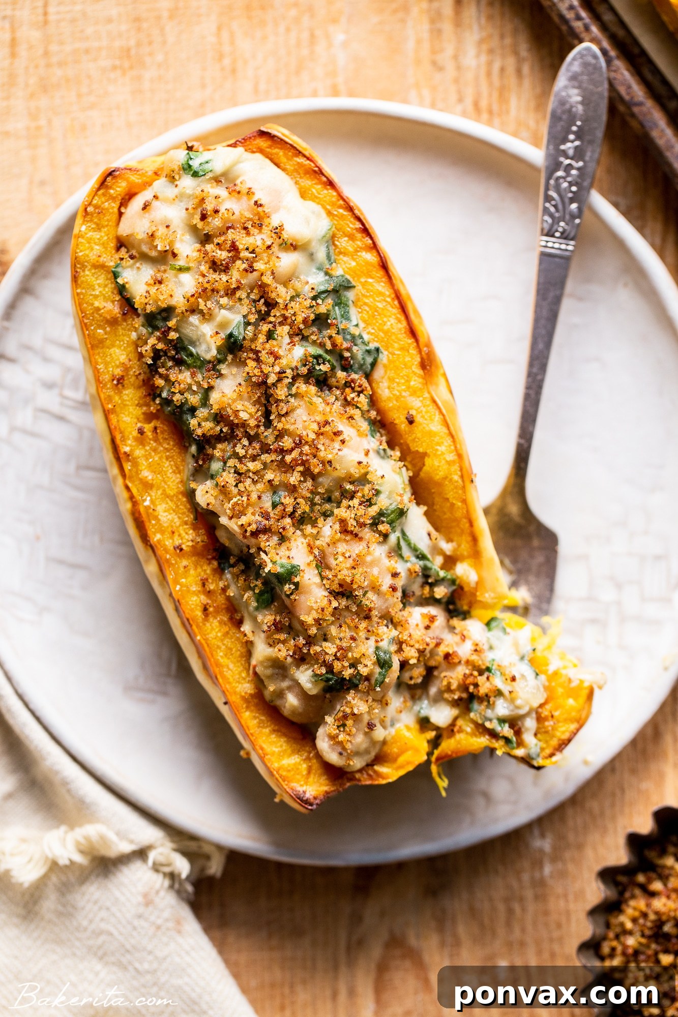 A close-up of a serving of Creamed Spinach & White Bean Stuffed Delicata Squash on a plate, ready to be eaten.