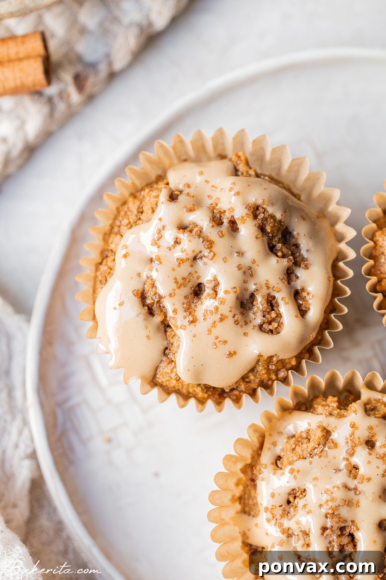 A stack of three Vegan Chai Muffins, beautifully glazed and ready to eat, on a wooden surface.