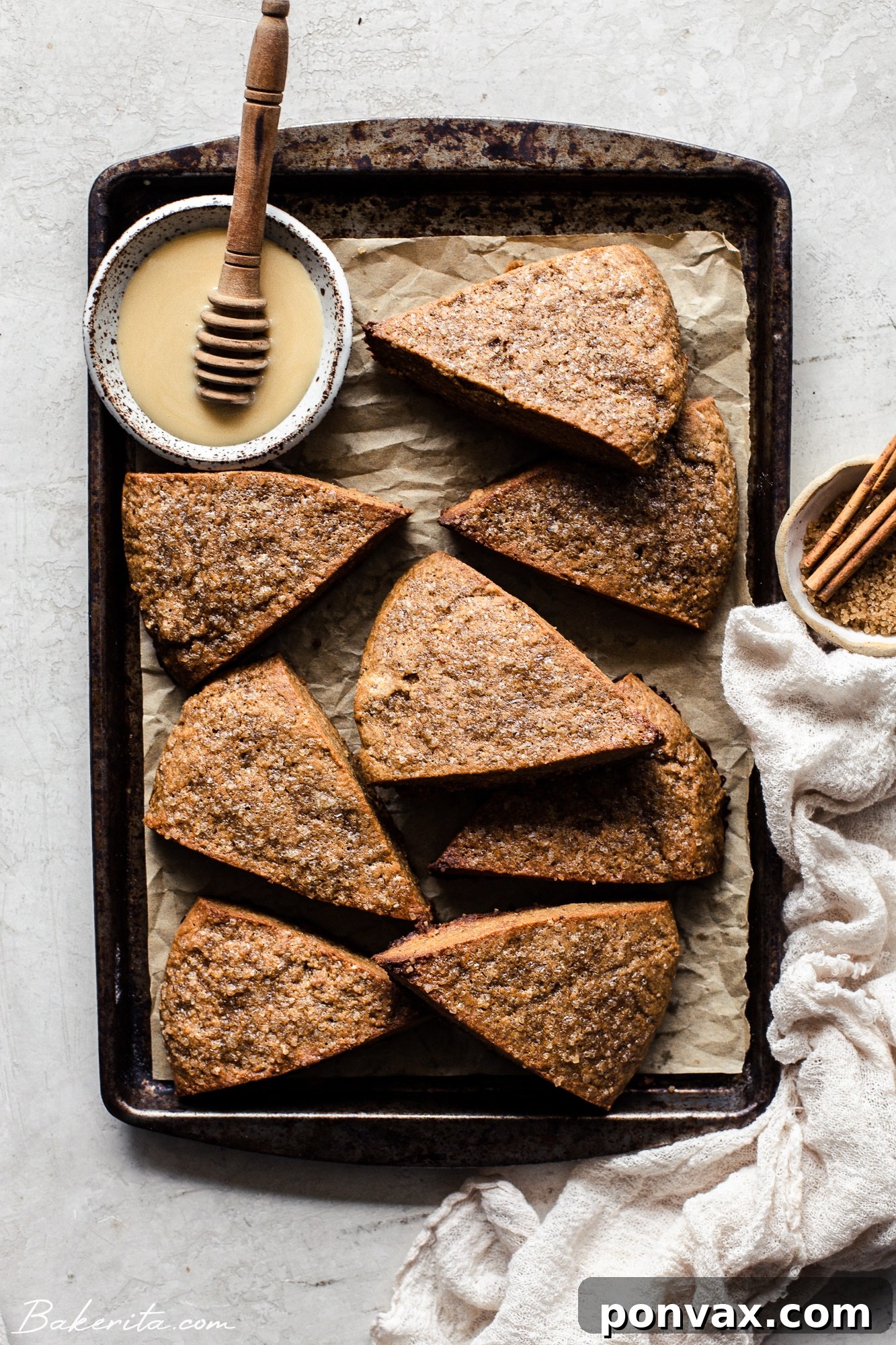 Three vegan gingerbread scones dusted with turbinado sugar, arranged on a cooling rack, highlighting their golden-brown edges.