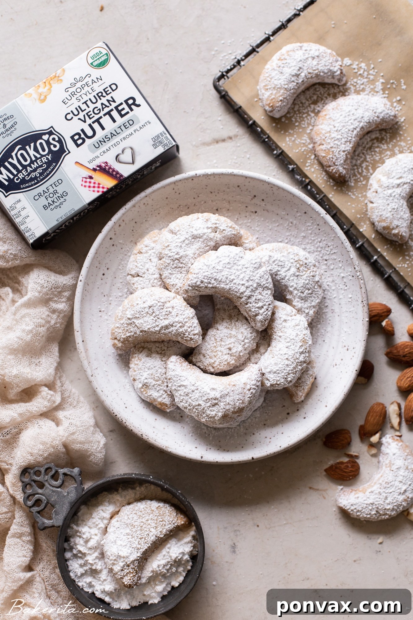 Close-up of golden brown Vegan Almond Crescent Cookies on a cooling rack before being dusted with powdered sugar.