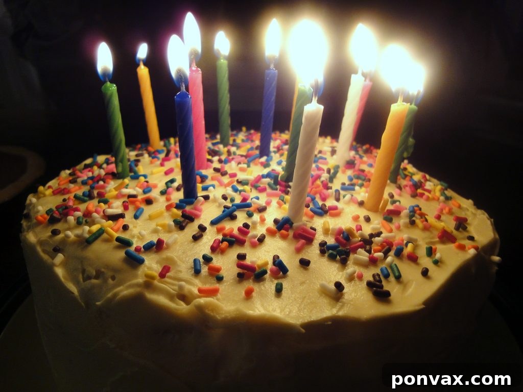 Sliced rainbow cake revealing its stunning layers Two vibrant slices of a six-layer rainbow cake with white frosting, showcasing the perfect separation of colors, on a simple white plate.