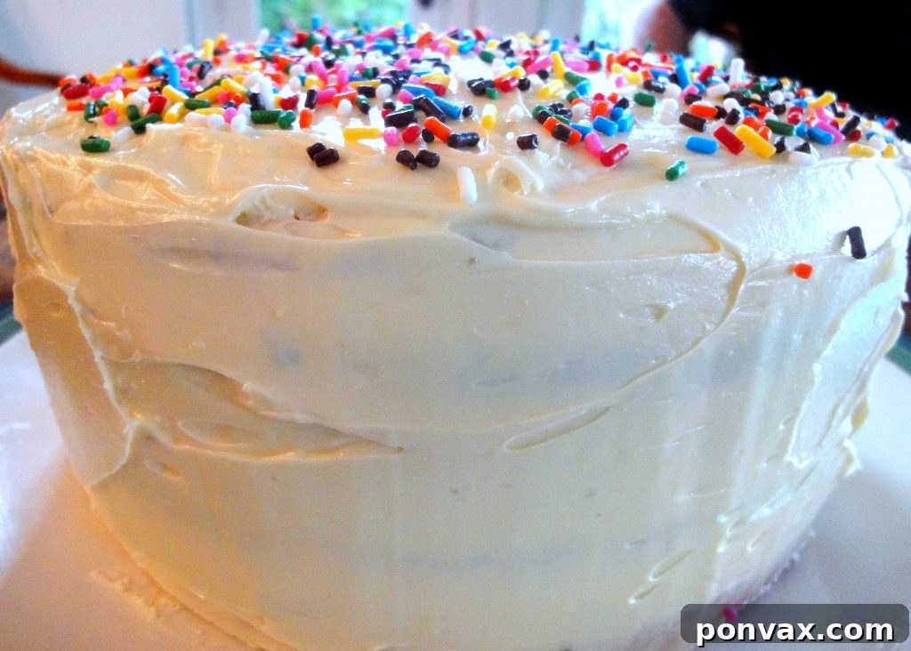 Applying creamy French buttercream to rainbow cake Close-up of fluffy French buttercream being generously spread between colorful cake layers, promising a smooth and less-sweet finish.