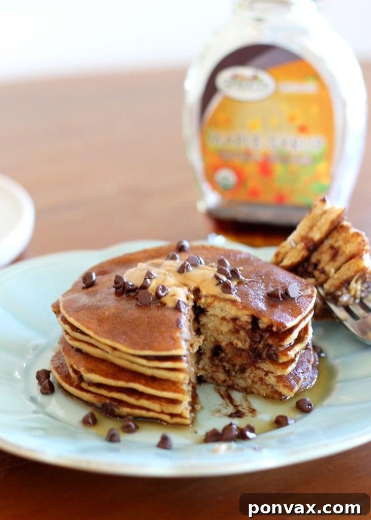 A stack of golden Banana Peanut Butter Protein Pancakes drizzled with maple syrup, showcasing their healthy and delicious appeal as a gluten-free breakfast.