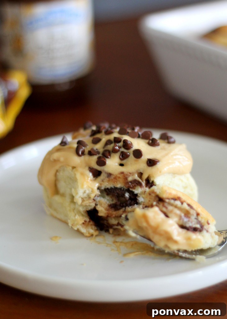 A stack of Chocolate Peanut Butter Sweet Rolls with generous swirls of Peanut Butter Cream Cheese Frosting.