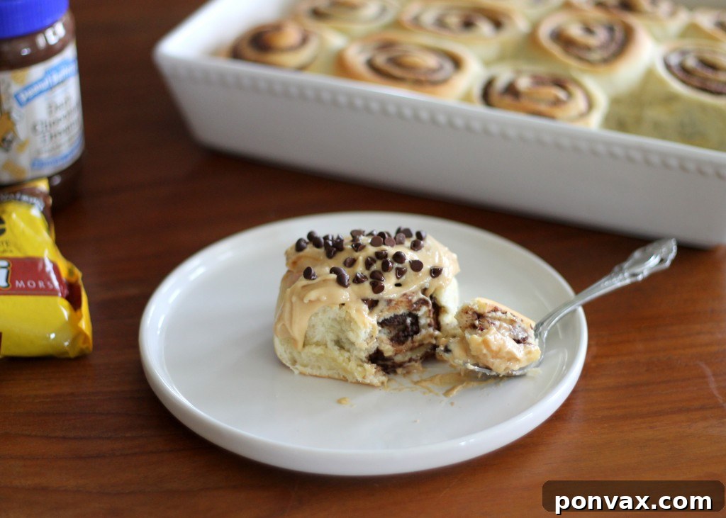 Close-up of a single Chocolate Peanut Butter Sweet Roll with generous Peanut Butter Cream Cheese Frosting, ready to be enjoyed.