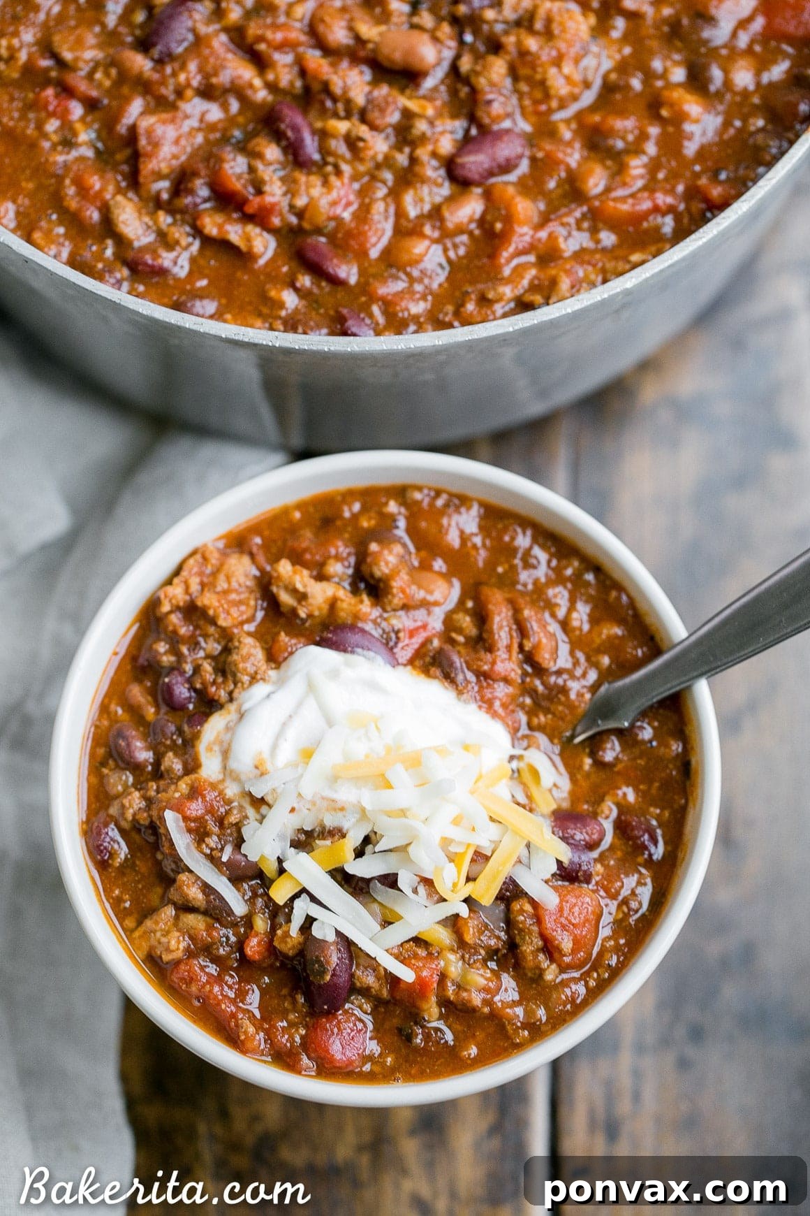 A steaming bowl of My Best Chili, garnished with shredded cheese, a spoonful of sour cream, and fresh cilantro, promising warmth and rich flavor.