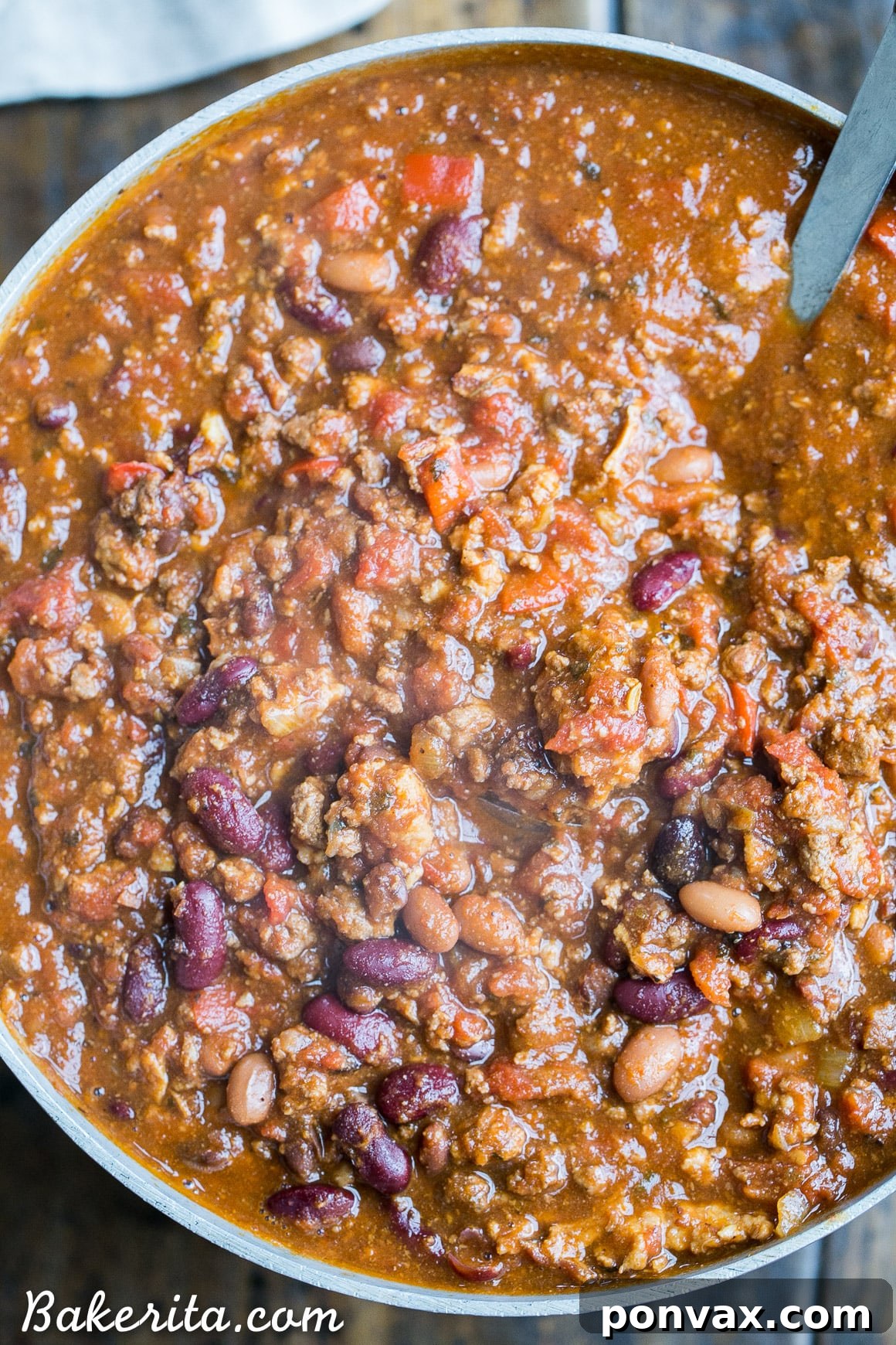 Close-up shot of My Best Chili simmering in a large pot, showcasing its rich, thick texture with visible chunks of meat and beans.