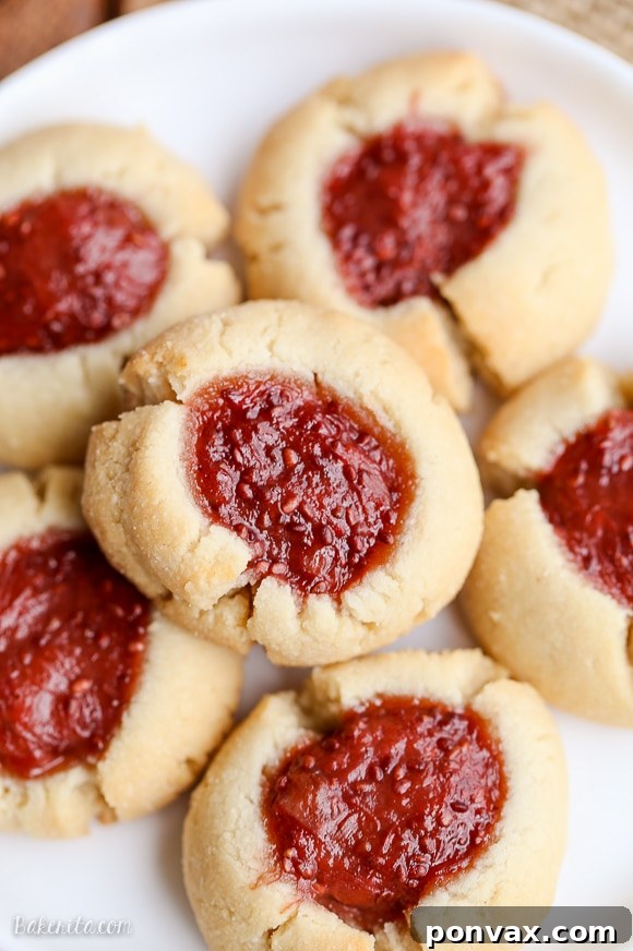 Simple & Sweet: Gluten-Free Vegan Jam Thumbprint Cookies 2 A white plate with a pile of Gluten-free and vegan Thumbprint Cookies, filled with a vibrant strawberry rhubarb chia jam, beautifully arranged.