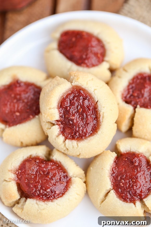 Simple & Sweet: Gluten-Free Vegan Jam Thumbprint Cookies 5 A white plate stacked with Gluten-free and vegan Thumbprint Cookies, each filled with luscious strawberry rhubarb chia jam, ready to be enjoyed.