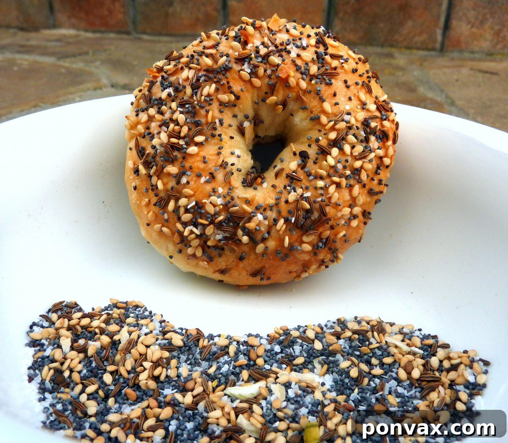 Golden brown homemade everything bagels fresh out of the oven, topped generously with sesame, poppy seeds, and garlic.