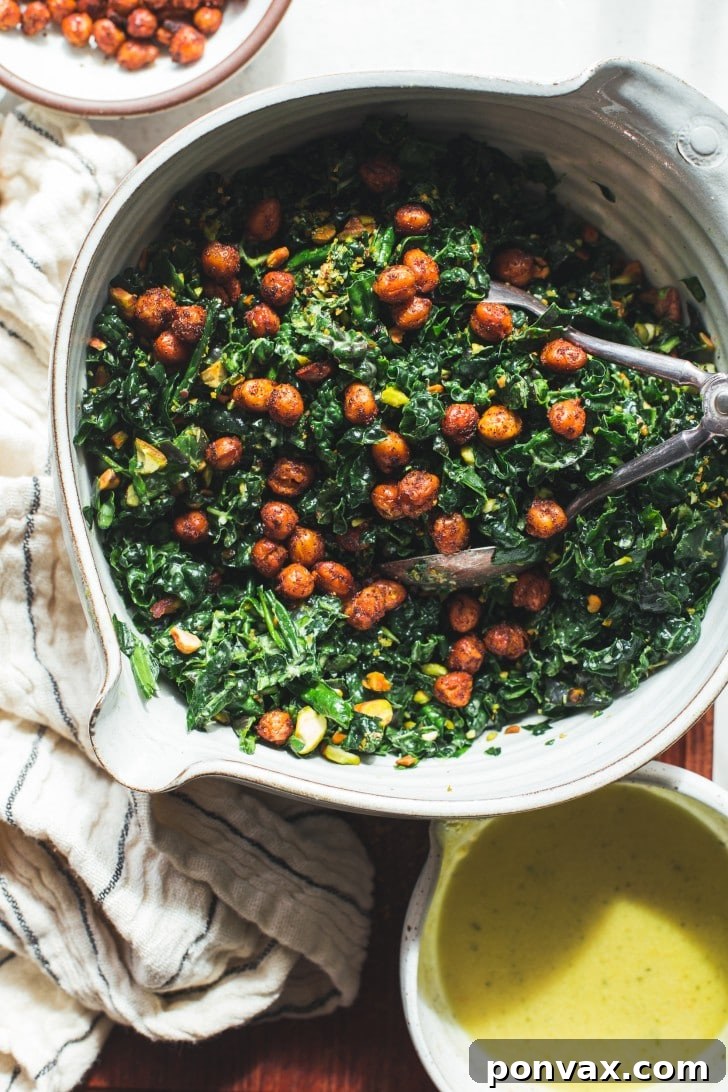 A serving of massaged kale chickpea salad on a plate, garnished with fresh herbs.