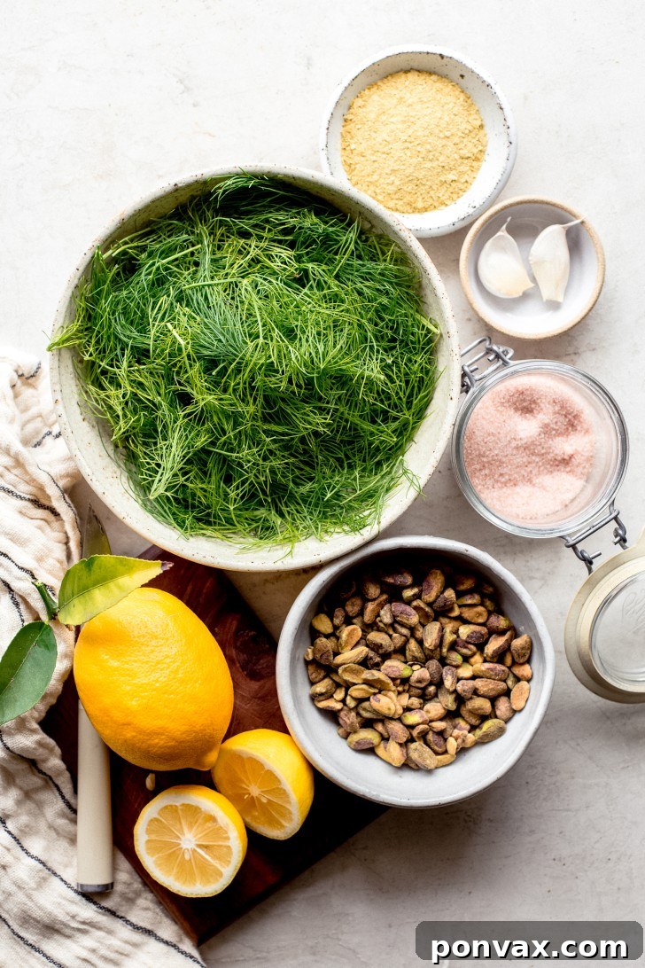 A selection of fresh ingredients for fennel frond pesto, including pistachios, lemons, garlic, and fennel fronds