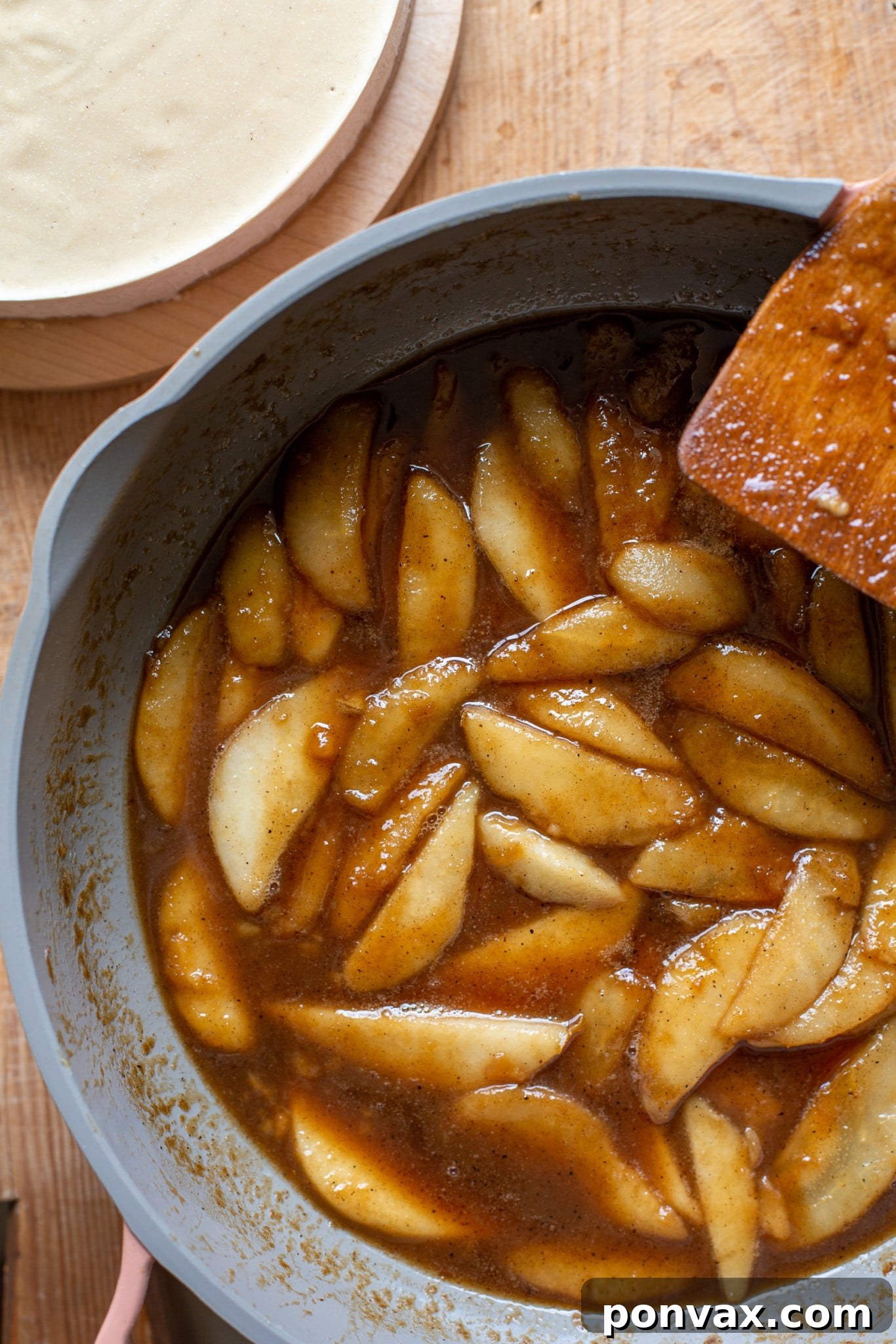 Hands pouring the smooth, vanilla-infused vegan cheesecake filling onto the almond flour crust.