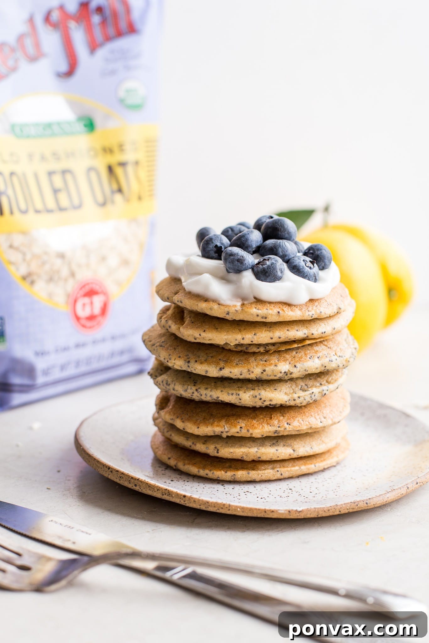 Stack of Vegan Lemon Poppyseed Pancakes with a dusting of powdered sugar.