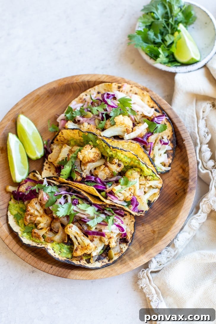 Zesty Roasted Cauliflower Tacos with Tangy Cabbage Slaw 2 Close-up of three Vegan Roasted Cauliflower Tacos with a side of slaw.