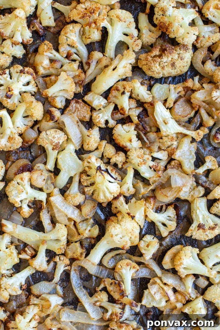 Zesty Roasted Cauliflower Tacos with Tangy Cabbage Slaw 3 A vibrant close-up shot of roasted cauliflower and sliced onions on a baking sheet, golden and caramelized.