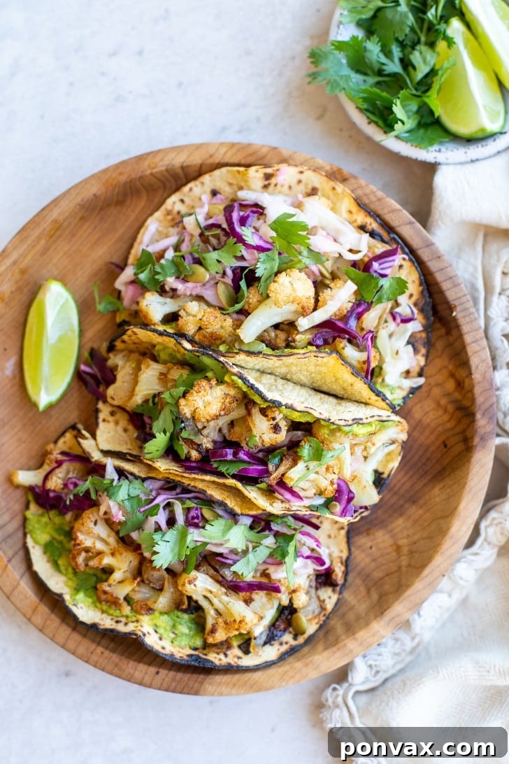 Zesty Roasted Cauliflower Tacos with Tangy Cabbage Slaw 7 A beautifully composed shot of three Vegan Roasted Cauliflower Tacos on a wooden board, ready to be enjoyed.