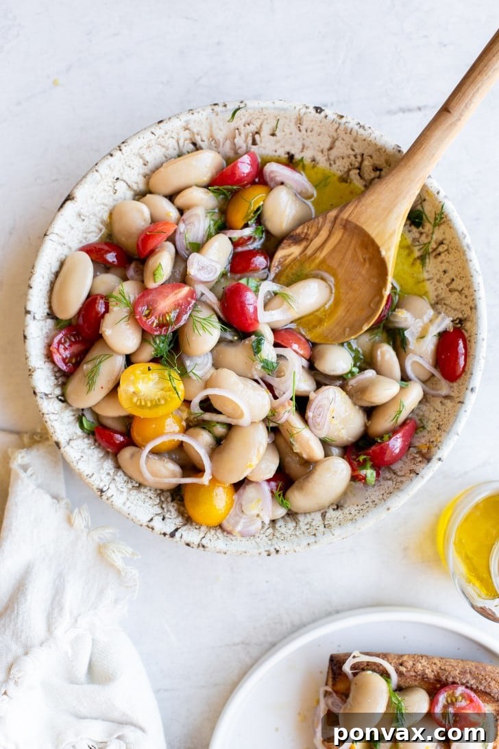 Another perspective of the Herby Marinated White Bean Salad, with a spoon resting in the bowl, ready to be served.