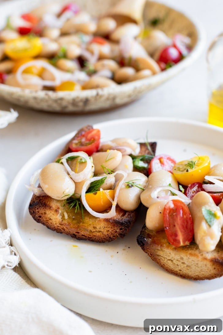 A vibrant bowl of Herby Marinated White Bean Salad with a focus on the fresh herbs and lemon zest.