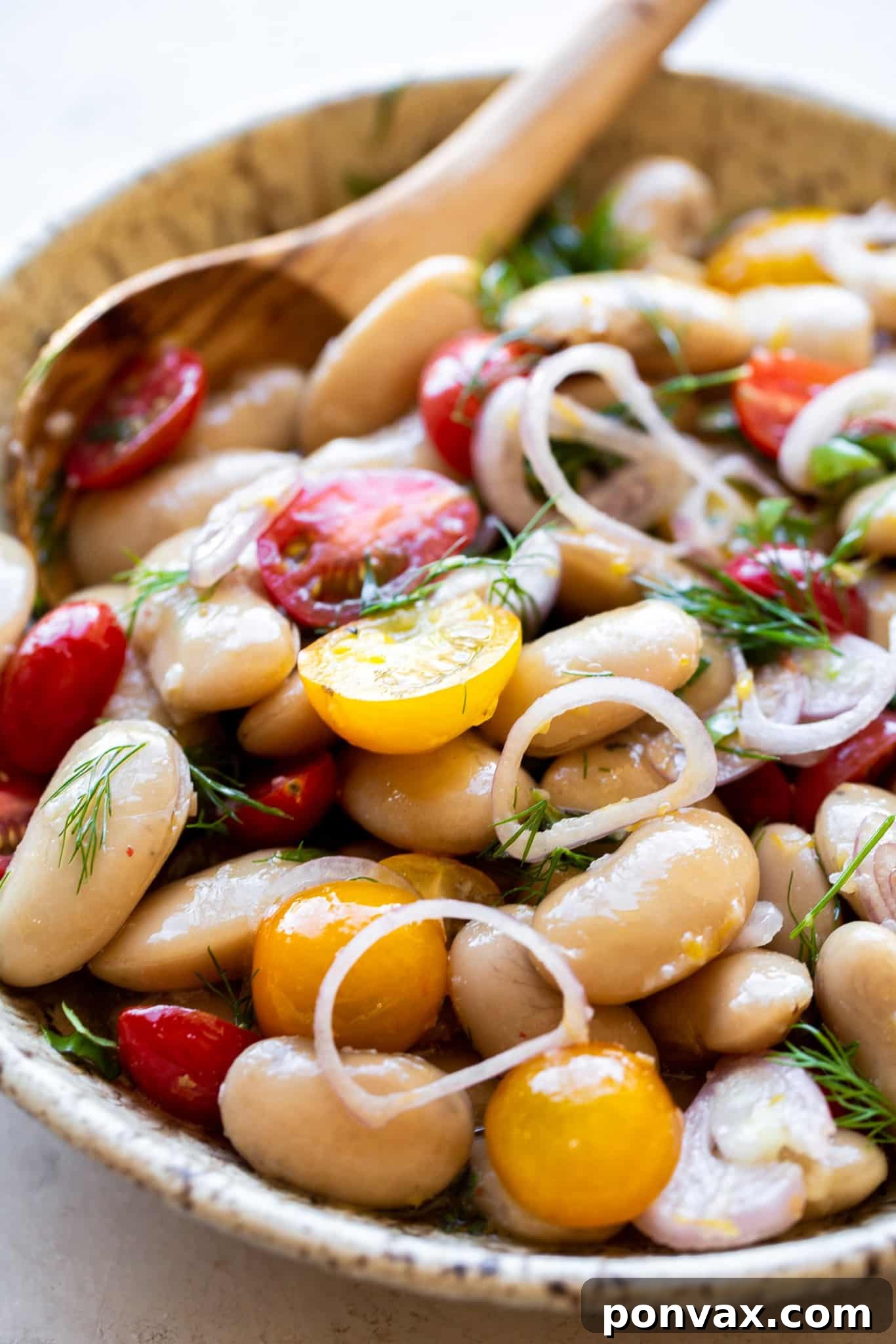 A top-down view of a serving of Herby Marinated White Bean Salad on toasted bread.