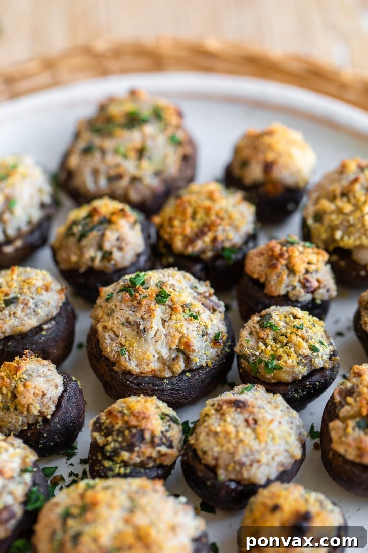 Savory Vegan Mushroom Bites 2 Close-up of baked vegan stuffed mushrooms garnished with fresh herbs, sitting on a wooden board.