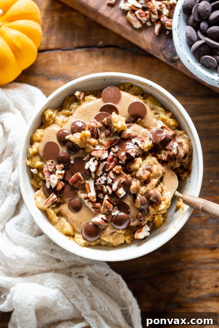 A bowl of freshly made Easy Pumpkin Oatmeal, steaming, with a spoon digging into its creamy texture, ready for toppings.