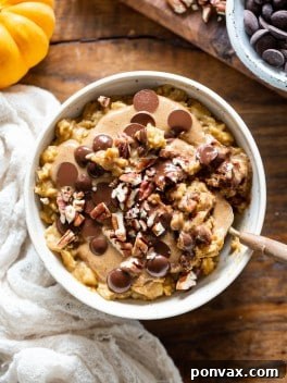 A bowl of creamy Easy Pumpkin Oatmeal, garnished with a sprinkle of pumpkin pie spice and a few pumpkin seeds.