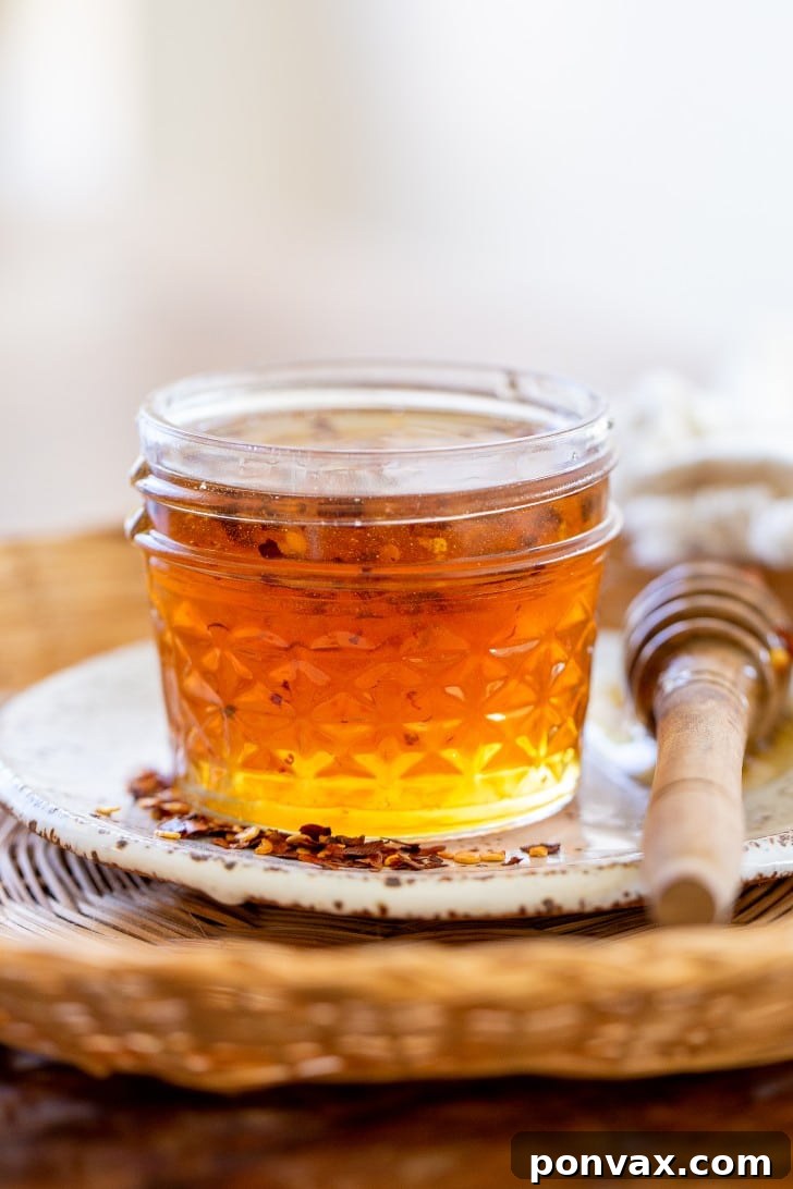 A jar of homemade hot honey, ready to be drizzled, sitting on a wooden surface.