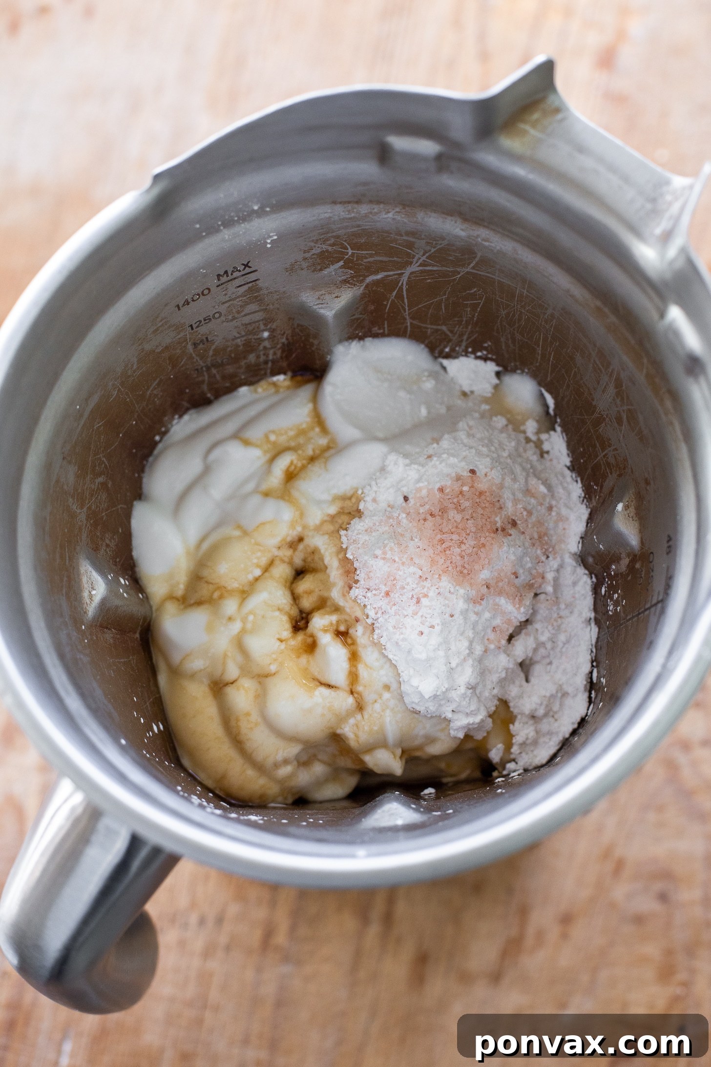 The smooth, creamy vegan cheesecake filling being poured over the pre-baked gluten-free oatmeal crust in a springform pan. The vibrant white filling stands out against the golden brown crust.