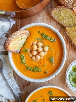 A comforting bowl of roasted tomato chickpea soup, garnished with fresh basil leaves.