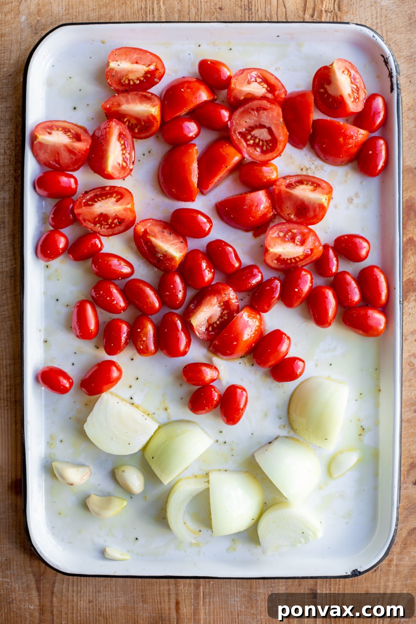 Sun Kissed Roasted Tomato and Chickpea Comfort 5 Fresh Roma and cherry tomatoes, quartered yellow onion, and whole garlic cloves precisely arranged on a baking sheet before roasting.