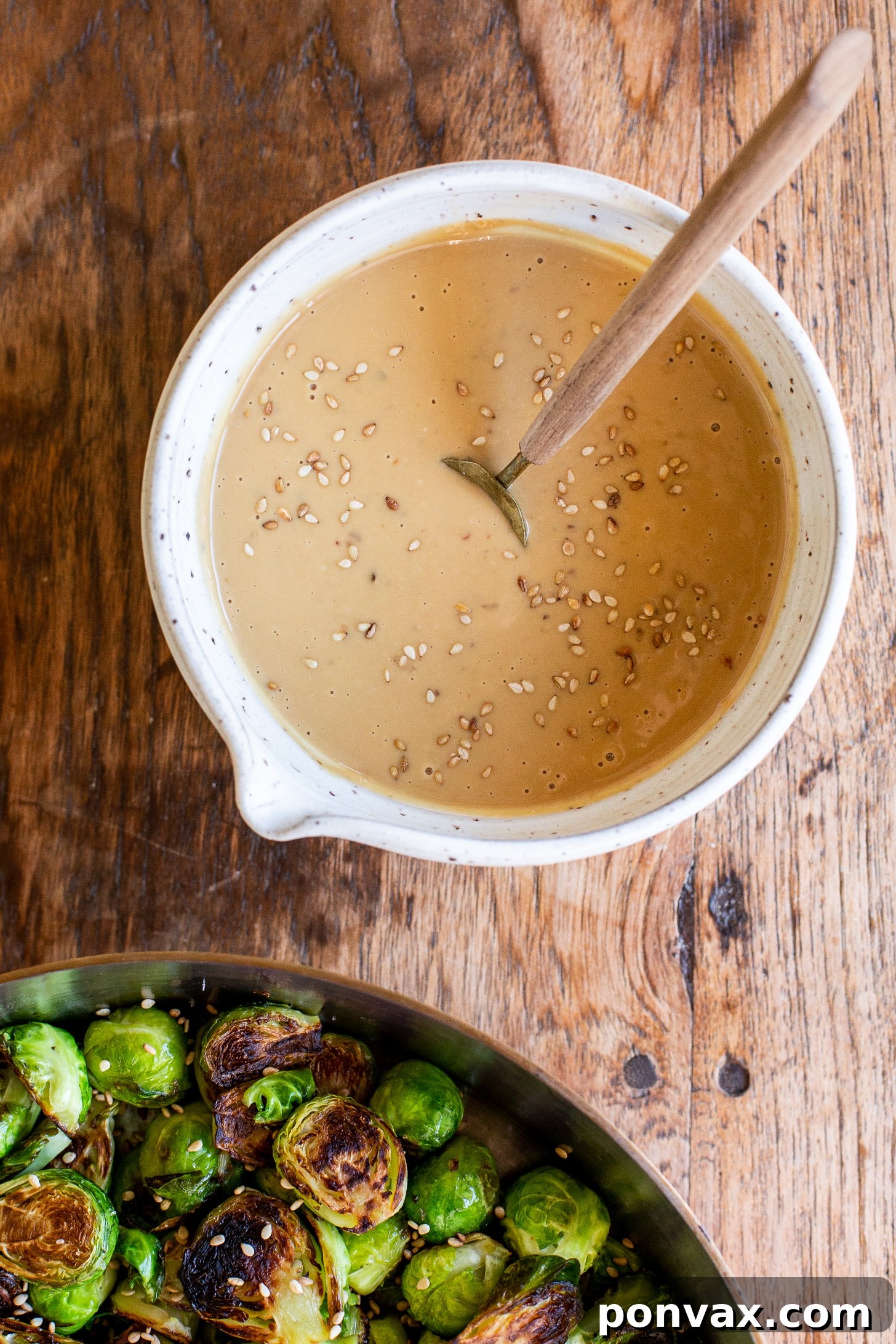 Glazed Miso Sesame Brussels Sprouts 5 A serving of Miso Sesame Brussels Sprouts garnished with fresh green onions and toasted sesame seeds, ready to be enjoyed.