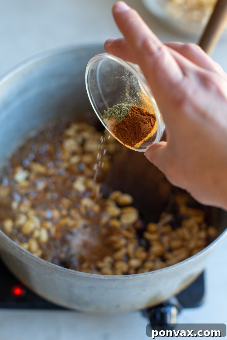 Puffed corn cereal being added to the pot with maple glaze and peanuts