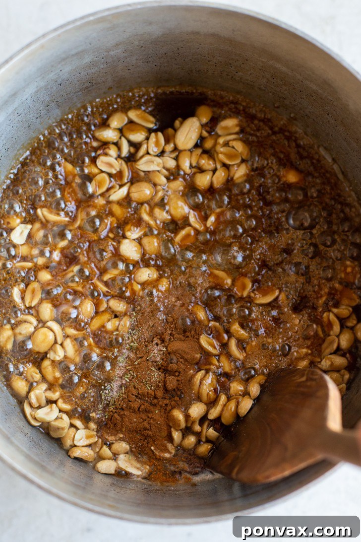 Puffed corn and peanuts being stirred in the pot to coat with maple glaze